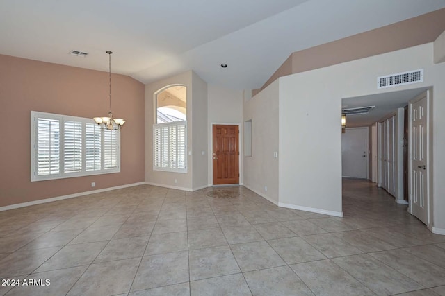 tiled spare room featuring high vaulted ceiling and a chandelier