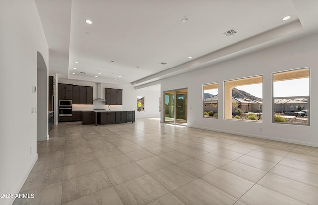 unfurnished living room featuring recessed lighting, a raised ceiling, visible vents, and baseboards