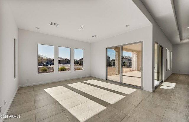 empty room featuring baseboards, light tile patterned floors, visible vents, and a healthy amount of sunlight