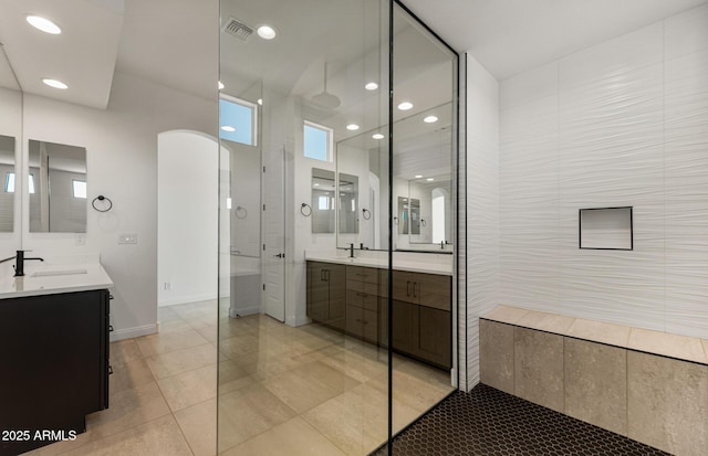 full bathroom featuring visible vents, a sink, a tile shower, two vanities, and recessed lighting