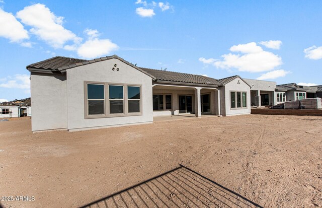 back of house featuring a patio area, a tile roof, and stucco siding