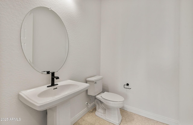 bathroom featuring toilet, baseboards, and a sink