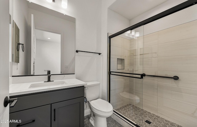 bathroom with vanity, a shower stall, and toilet