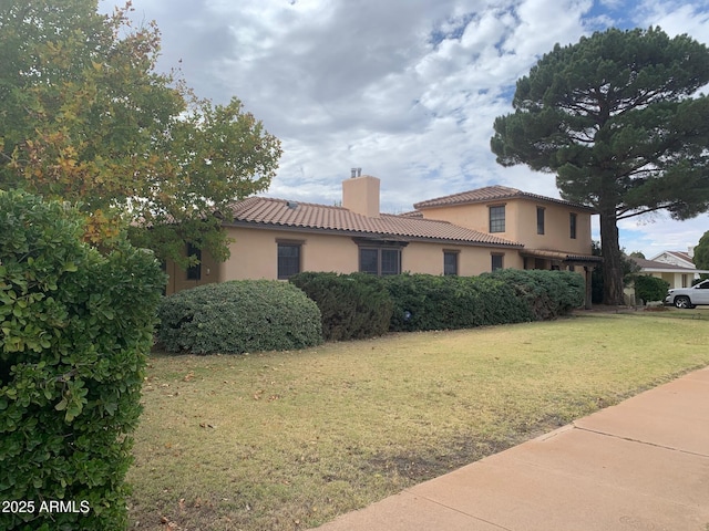 1565 E 12th St, Douglas, AZ 85607 - view of property exterior featuring a chimney, stucco siding, a tile roof, and a lawn
