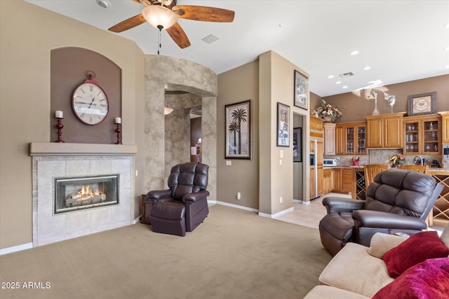 carpeted living room featuring a tiled fireplace and ceiling fan