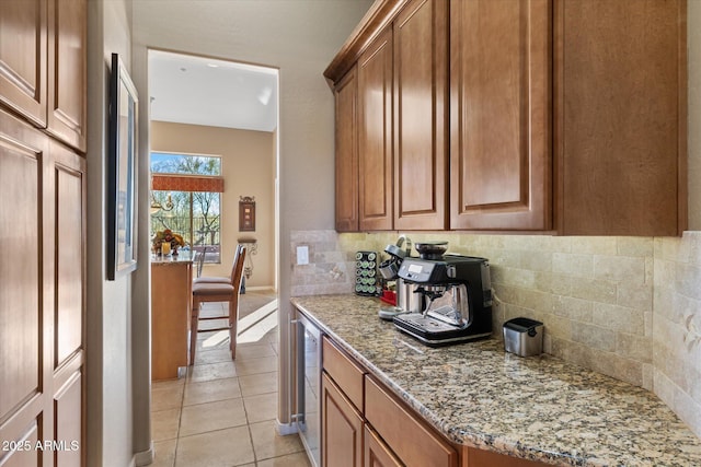 kitchen with light stone counters, light tile patterned floors, stainless steel fridge, beverage cooler, and decorative backsplash