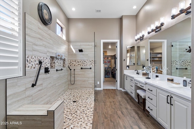 bathroom with tiled shower, vanity, and wood-type flooring