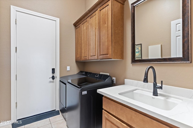 washroom with light tile patterned flooring, cabinets, washer and clothes dryer, and sink