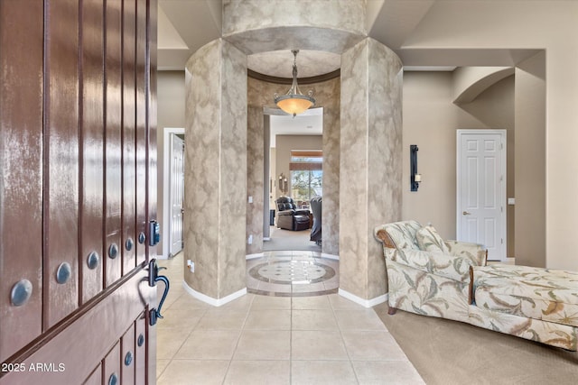 entryway featuring a high ceiling, light tile patterned floors, and ornate columns