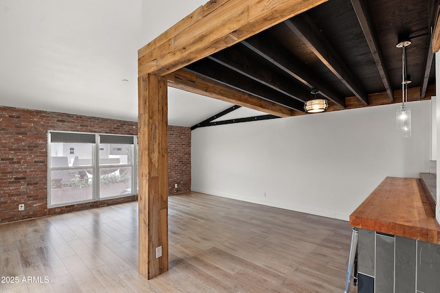 5621 N 79th St, Scottsdale, AZ 85250 - unfurnished living room with brick wall, beamed ceiling, wood finished floors, and baseboards