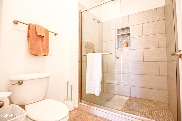 full bath featuring toilet, a shower stall, and tile patterned flooring
