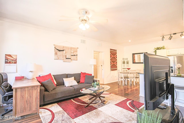 living area with baseboards, a ceiling fan, ornamental molding, and wood finished floors