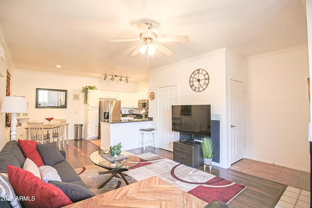 living room with crown molding, baseboards, and a ceiling fan
