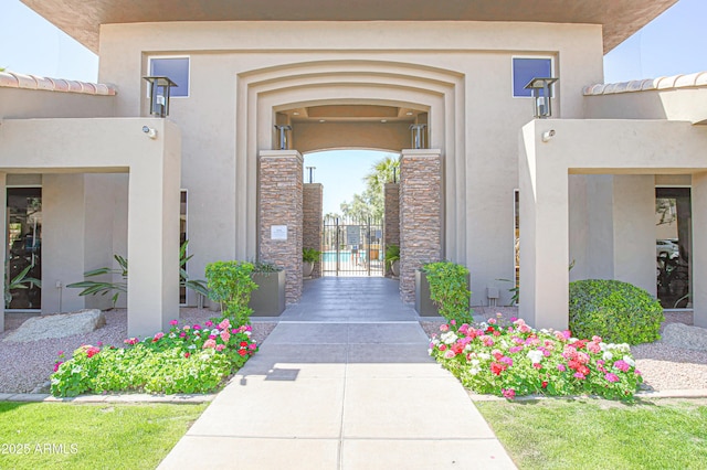 doorway to property featuring stone siding, a gate, and stucco siding