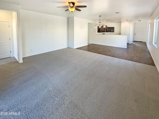 unfurnished living room with ceiling fan and dark colored carpet