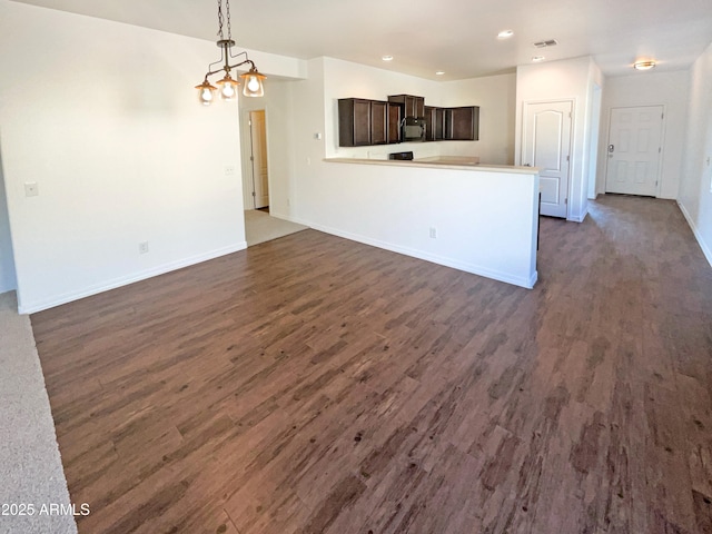 unfurnished living room with dark hardwood / wood-style floors and an inviting chandelier