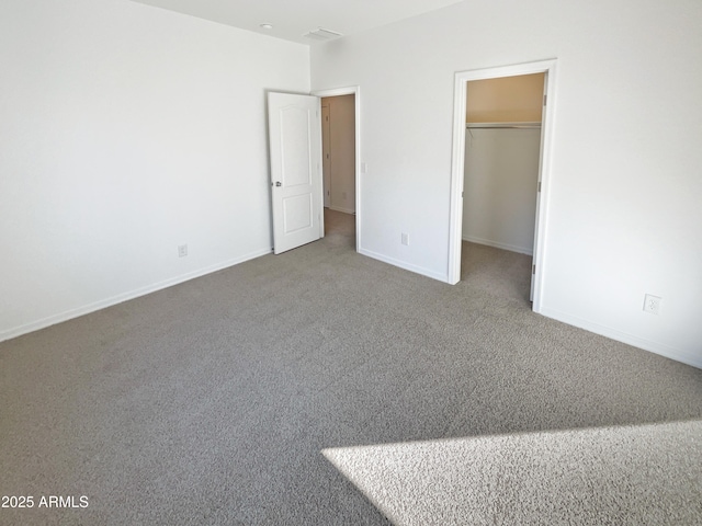 unfurnished bedroom with a spacious closet and carpet