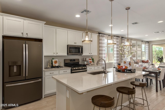 kitchen featuring white cabinetry, stainless steel appliances, tasteful backsplash, and a sink
