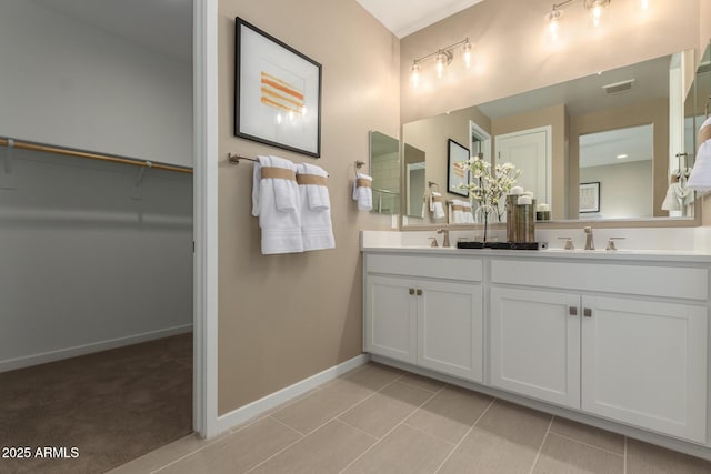 full bath featuring double vanity, baseboards, a spacious closet, and a sink