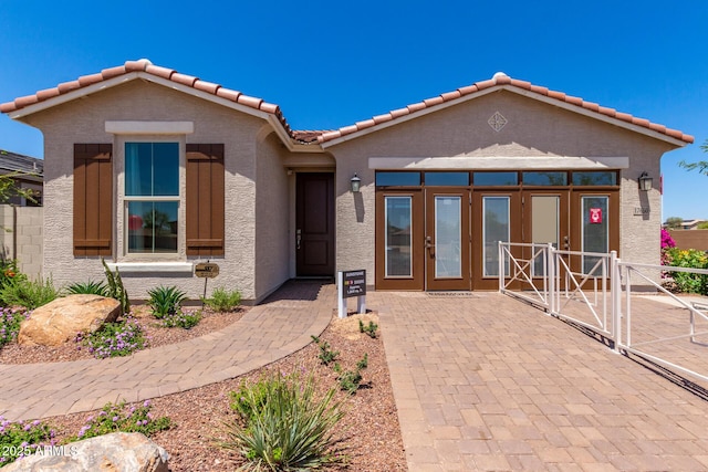 ranch-style home featuring a tiled roof, stucco siding, french doors, and fence