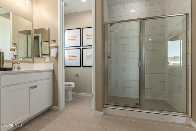 full bath featuring toilet, vanity, a stall shower, tile patterned flooring, and baseboards