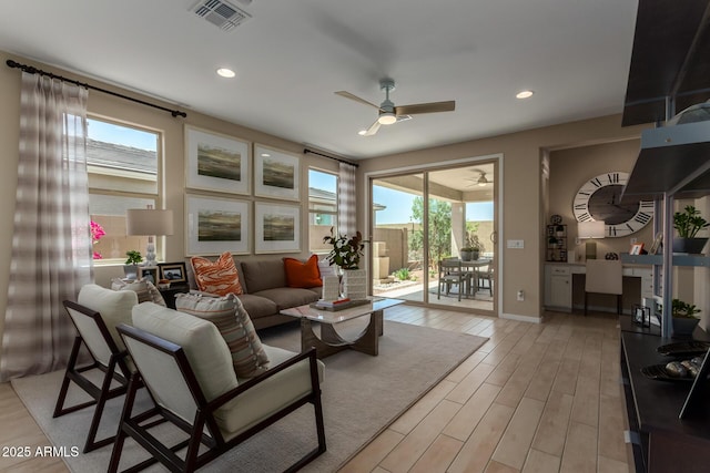 living area featuring ceiling fan, light wood-style floors, visible vents, and plenty of natural light