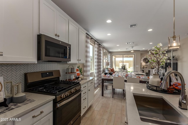 kitchen featuring recessed lighting, a sink, white cabinetry, backsplash, and appliances with stainless steel finishes