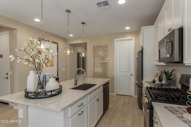 kitchen with visible vents, a sink, a center island with sink, white cabinets, and appliances with stainless steel finishes