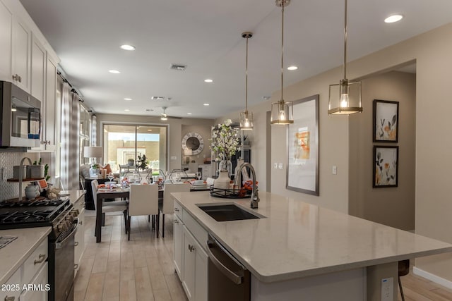 kitchen with a sink, light wood finished floors, stainless steel appliances, and recessed lighting