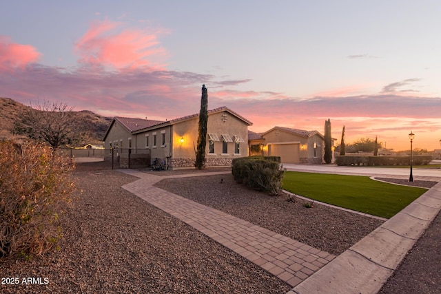 view of front of house with fence, driveway, an attached garage, stucco siding, and a lawn