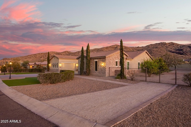 view of front of house featuring fence, stucco siding, stone siding, driveway, and a gate