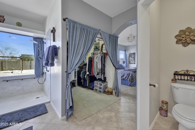 ensuite bathroom featuring toilet, a walk in shower, and tile patterned floors