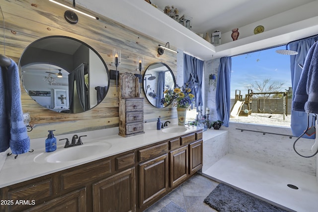 full bathroom with double vanity, tile patterned flooring, a shower, and a sink