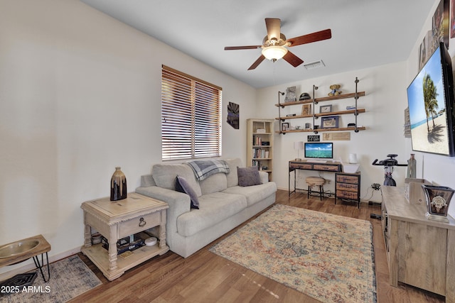 living room with ceiling fan, visible vents, and wood finished floors