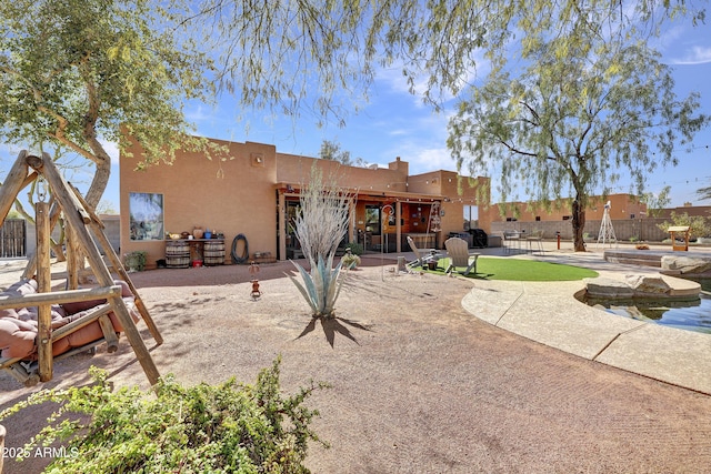 rear view of property with a patio area, fence, and stucco siding