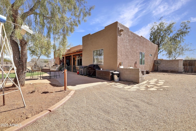 view of property exterior with fence, a patio, an outdoor kitchen, and stucco siding