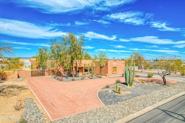 adobe home with a gate and stucco siding