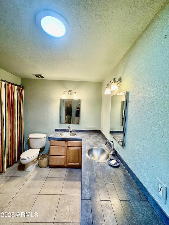 bathroom featuring vanity, a shower with shower curtain, visible vents, a textured ceiling, and toilet