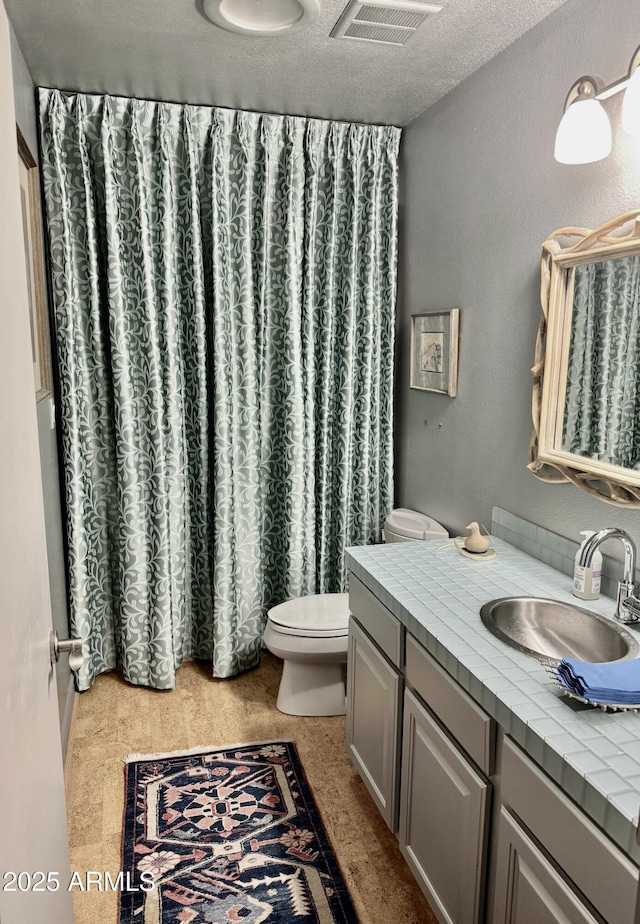 bathroom featuring visible vents, toilet, vanity, and a textured ceiling