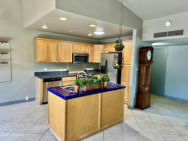 kitchen featuring visible vents, a kitchen island with sink, tile countertops, appliances with stainless steel finishes, and light tile patterned flooring