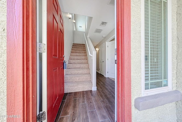 foyer with visible vents, stairs, and dark wood-style flooring