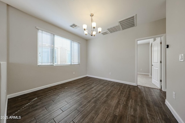 unfurnished room with dark wood finished floors, visible vents, baseboards, and an inviting chandelier