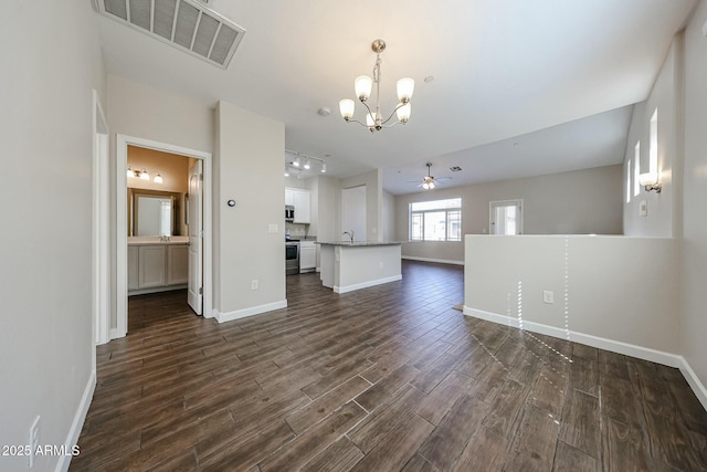 unfurnished living room featuring visible vents, ceiling fan with notable chandelier, dark wood-style floors, rail lighting, and baseboards