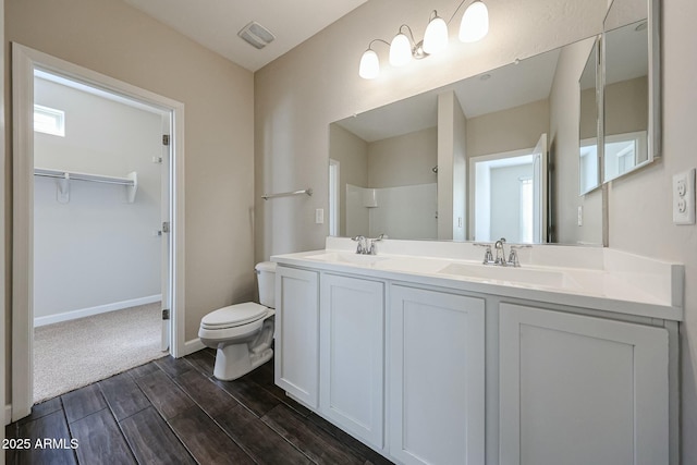 bathroom with double vanity, toilet, wood tiled floor, and a sink