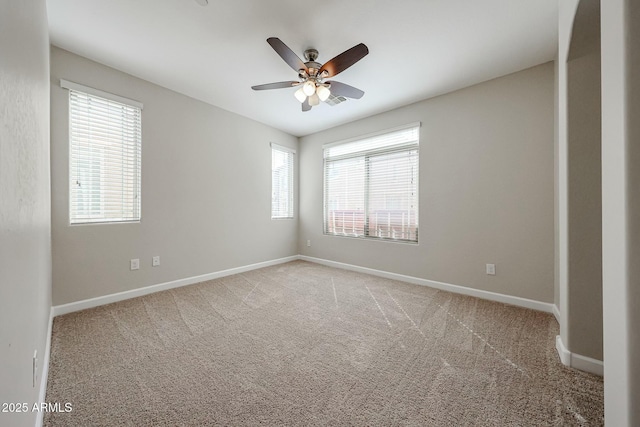 carpeted spare room featuring baseboards and a ceiling fan