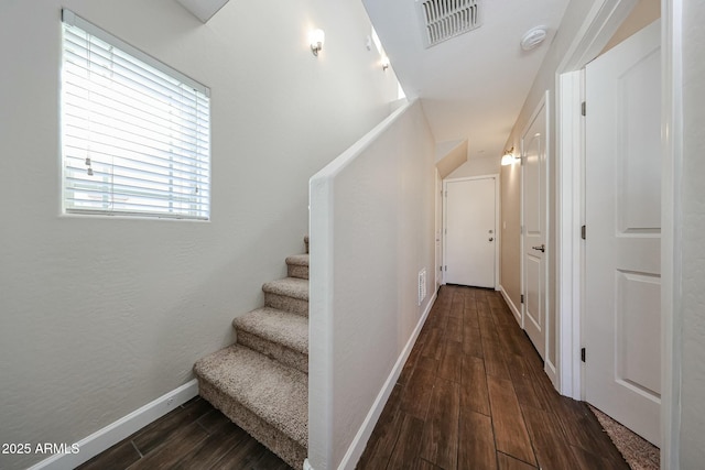 stairway featuring wood finished floors, visible vents, and baseboards