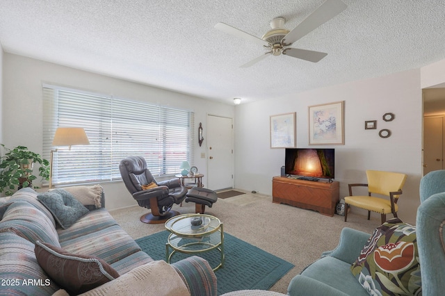 living room featuring ceiling fan, light colored carpet, and a textured ceiling