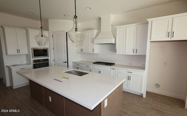 kitchen featuring dark hardwood / wood-style flooring, pendant lighting, a kitchen island with sink, appliances with stainless steel finishes, and custom exhaust hood