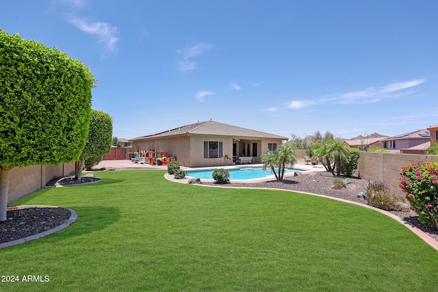 rear view of house featuring a patio area, a lawn, and a fenced in pool