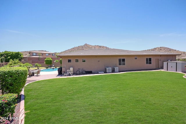 back of property featuring a yard, a fenced in pool, central air condition unit, and a storage shed